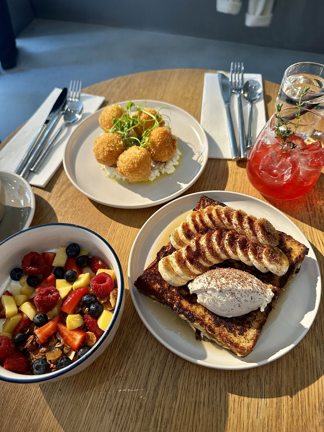 Breakfast at Perl: French toast with banana, cheese croquettes, a fruit and granola bowl and an iced tea with thyme