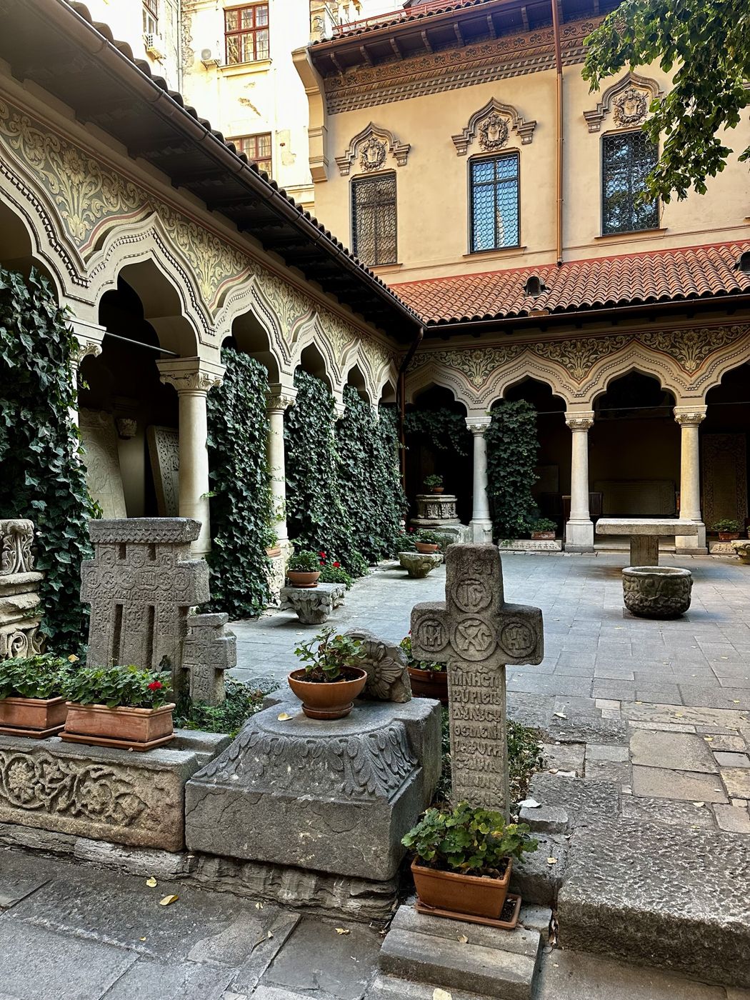 The ivy-covered arched courtyard of Stavropoleos Monastery with old carved stone crosses