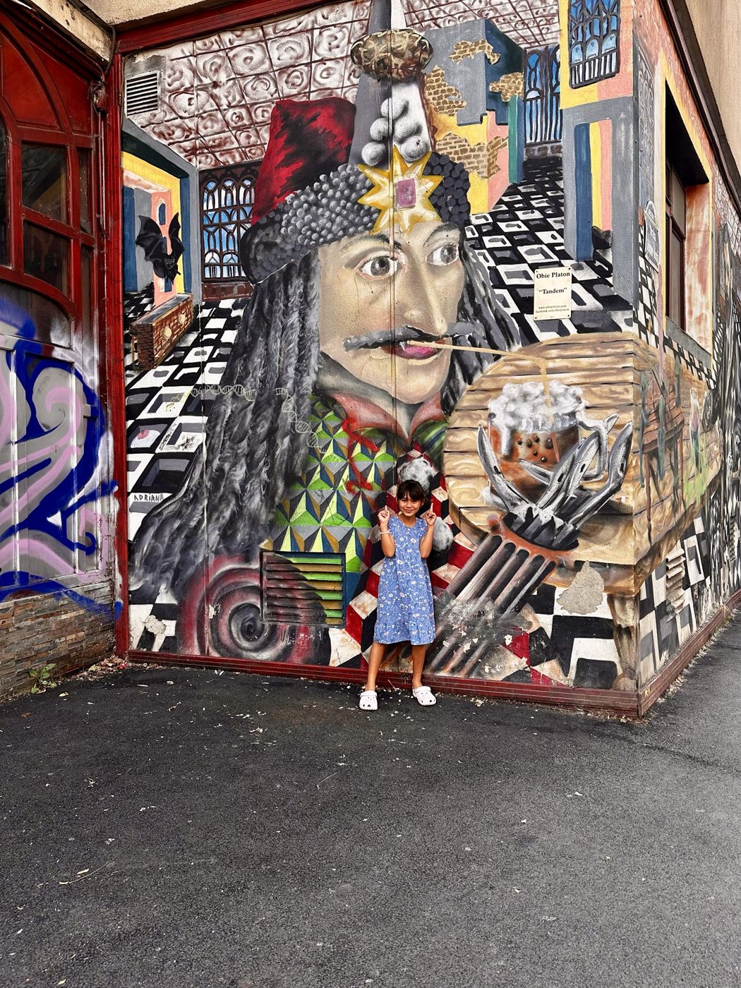 Olivia posing in front of a colorful mural of Vlad the Impaler