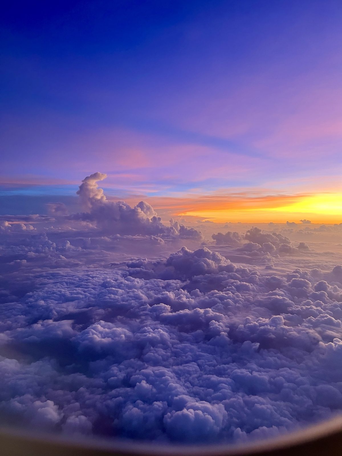 A sea of violet clouds at sunset, seen from an airplane window