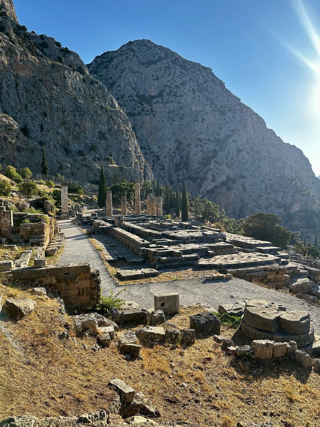 The Temple of Apollo at Delphi beneath towering limestone cliffs in morning light