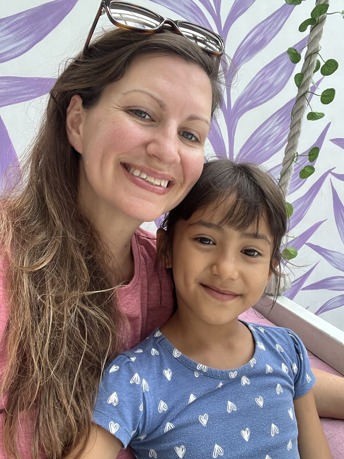 Brittany and one of her daughters smiling in front of a painted mural
